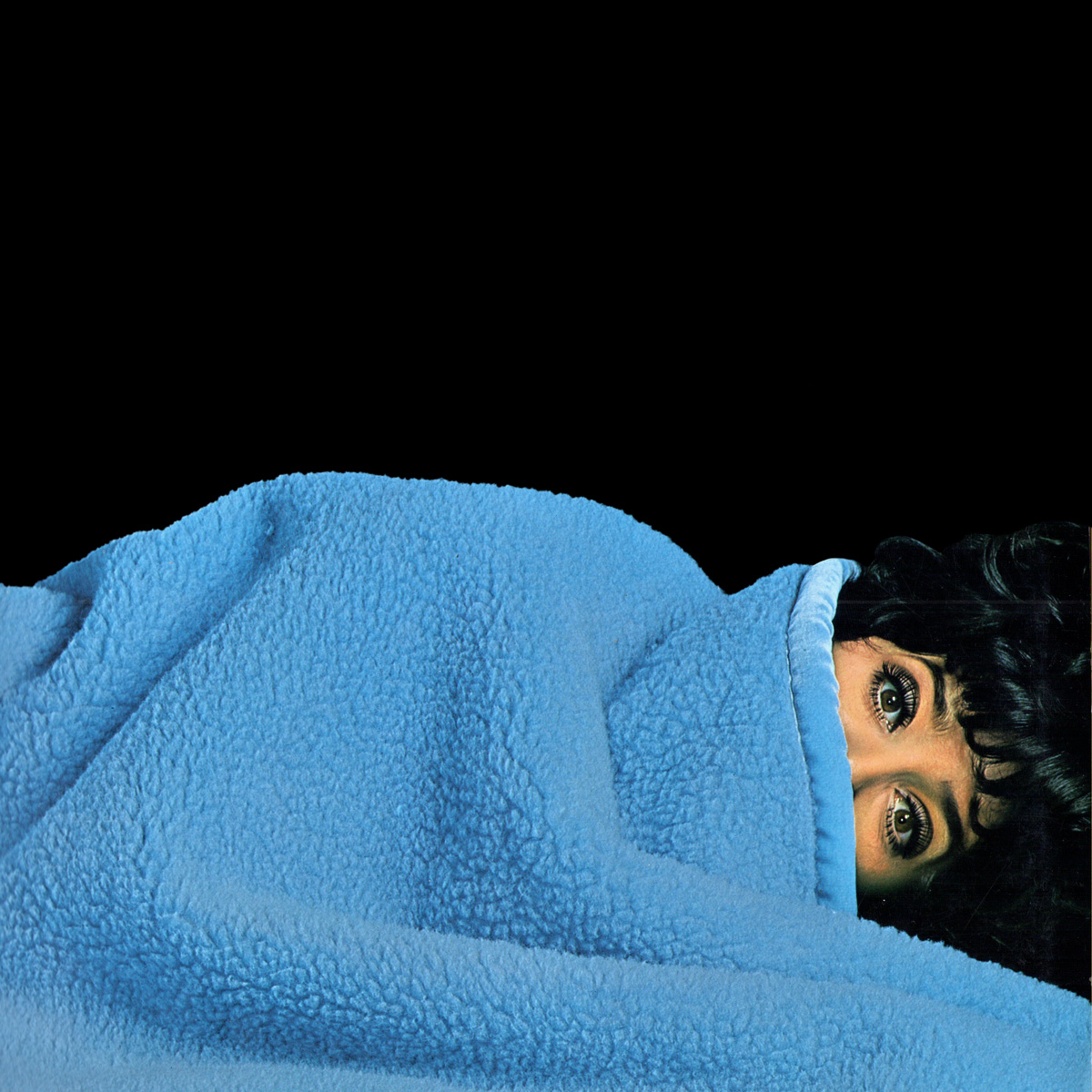 181012_1969_1200x1200px Das Katalog-Cover zeigt eine Frau, die bis zu den Augen unter einer blauen Wohndecke liegt.